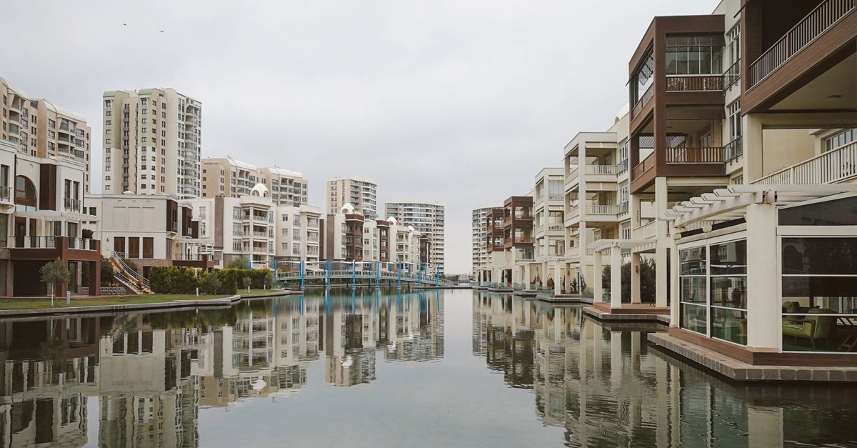 Modern residential buildings reflecting in a tranquil urban canal.