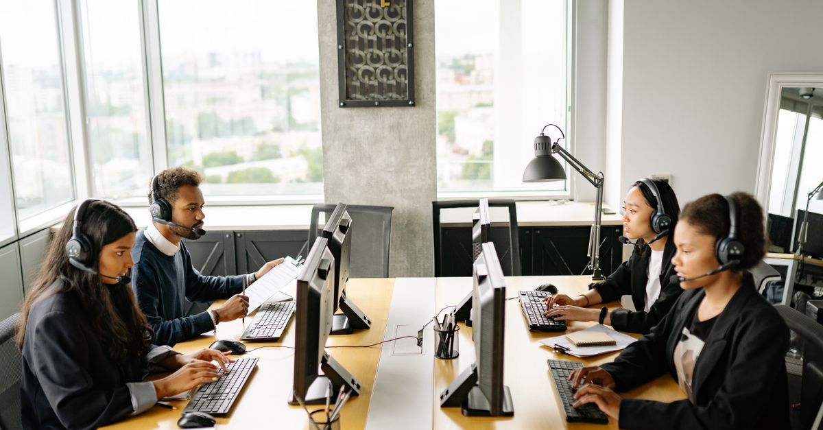 Group of diverse employees working together in a modern office setting, focusing on customer service.